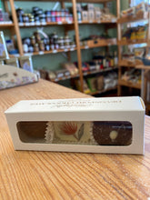 Box of chocolates with a clear window on a wooden surface, blurred store shelves in the background