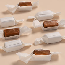 Caramel bars in white wrappers on a beige background